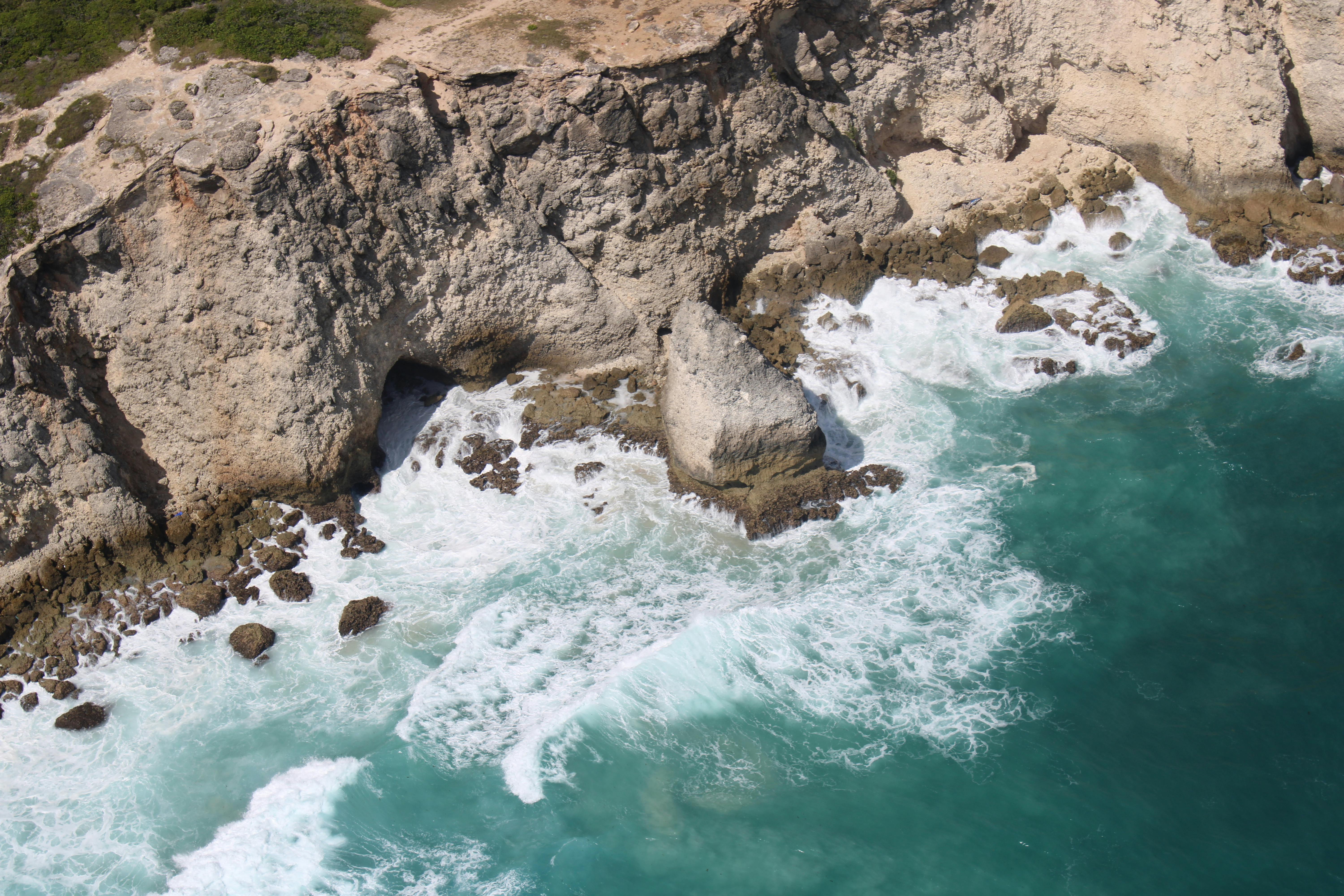 Vagues s’écrasant sur une côte rocheuse avec des rochers et une petite grotte marine.